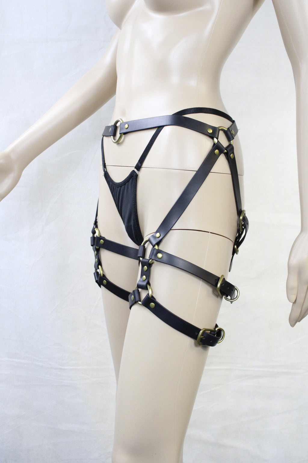 A mannequin wearing a black leather strap with multiple buckles and straps, creating an intricate and detailed appearance.