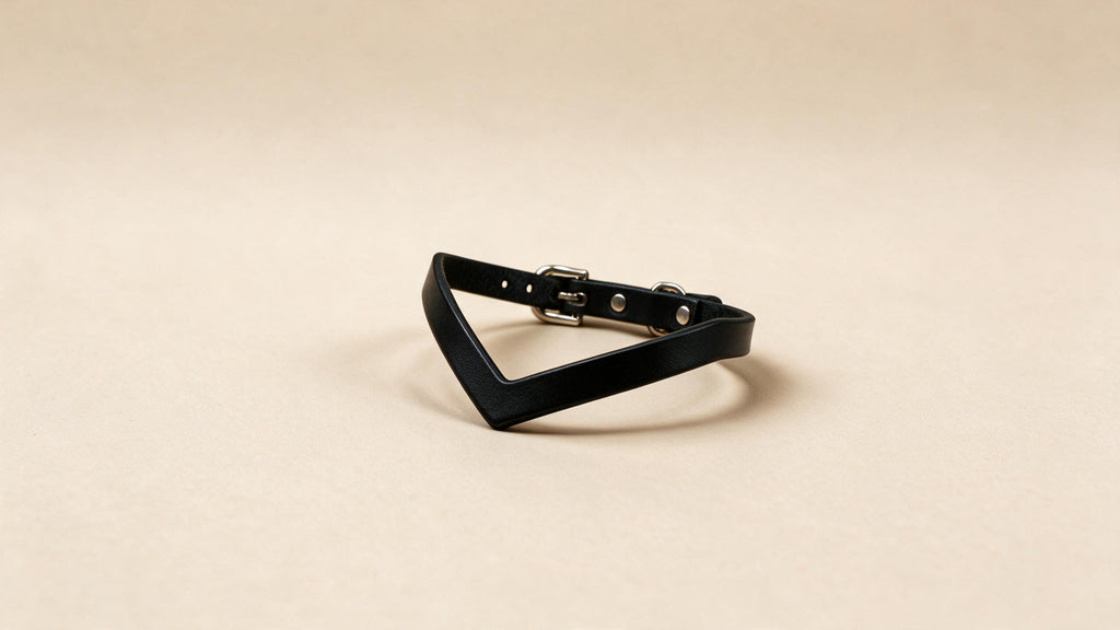 A black leather bracelet with a unique, triangular-shaped design is shown against a light beige background.