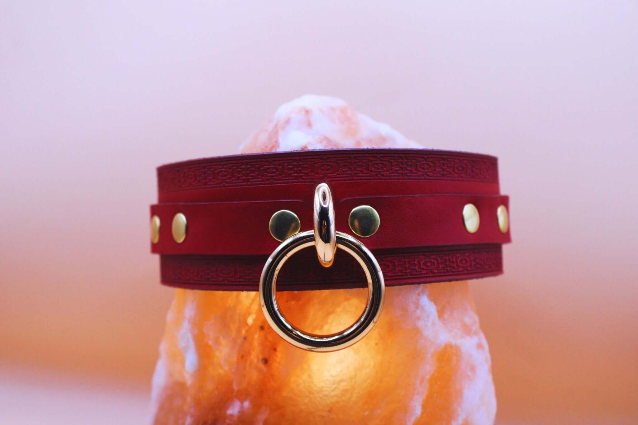 Crimson red BDSM collar featuring gold-tone O-ring, designed for submissive elegance and bondage aesthetics.