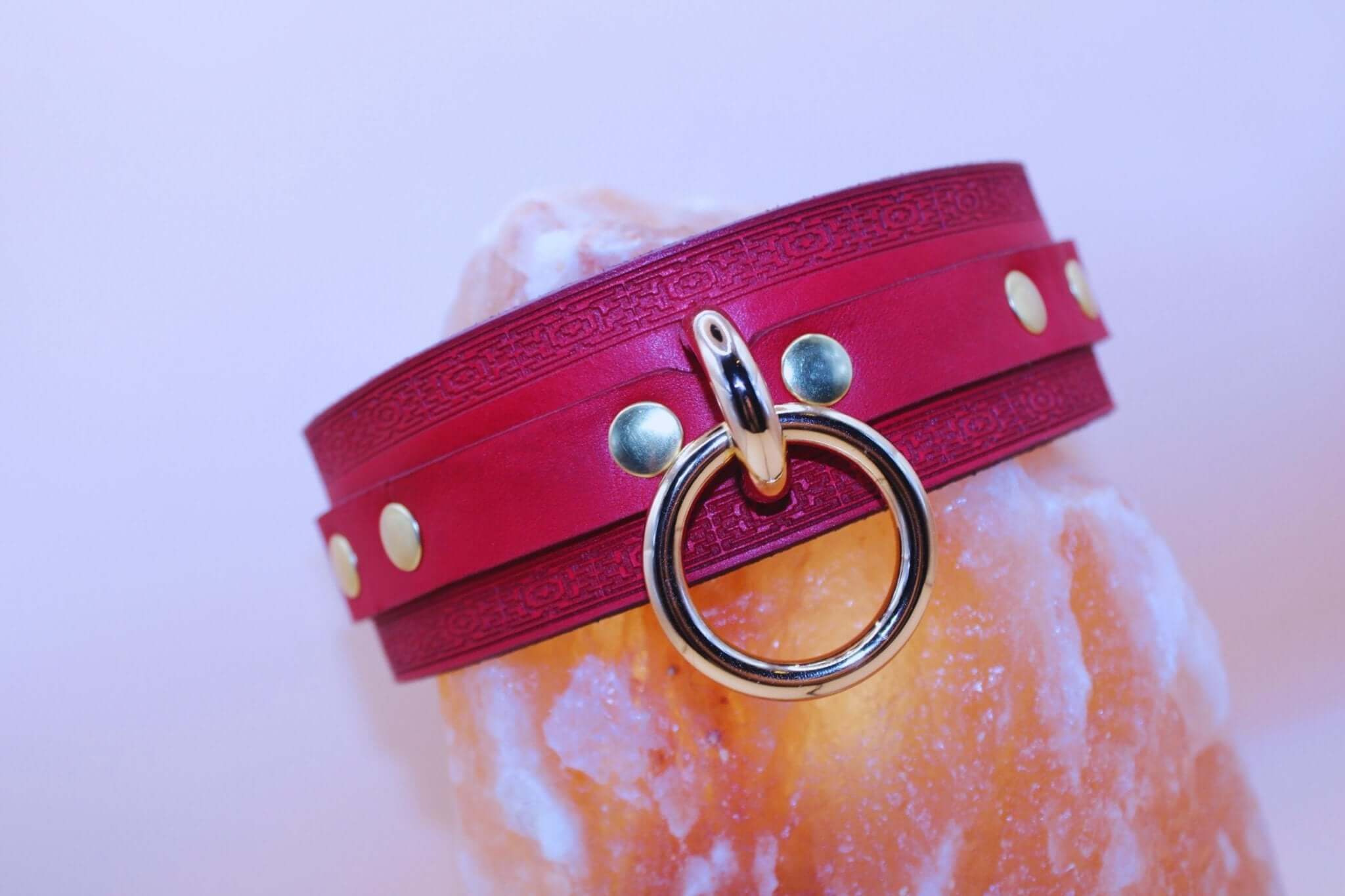Elegant crimson red BDSM collar with gold-tone O-ring and embossed leather, perfect for power dynamics and fashion.
