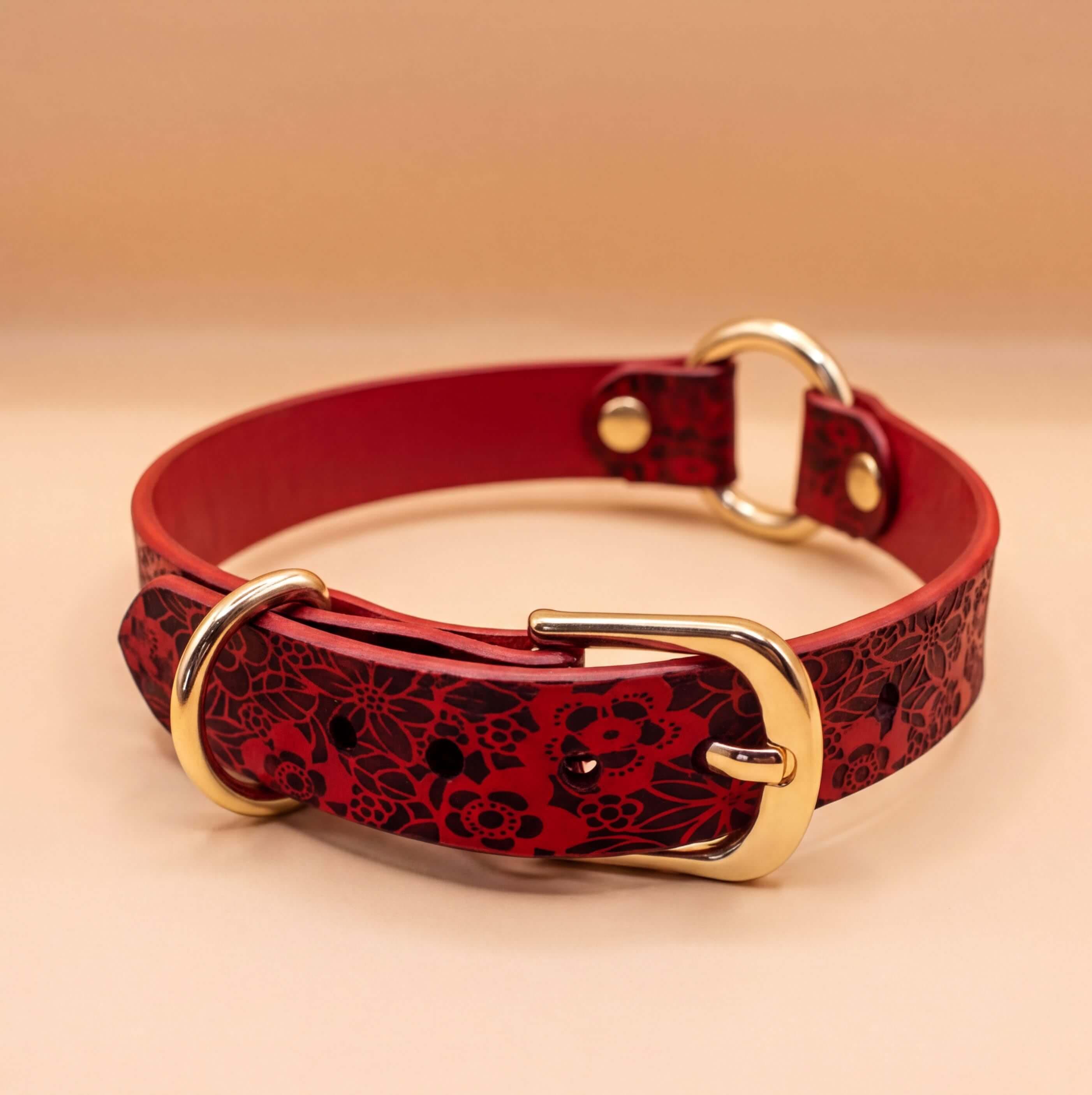 A red leather collar with a floral pattern and a gold buckle.