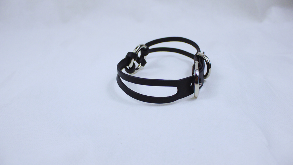 A black leather bracelet with silver buckles is shown against a white background.