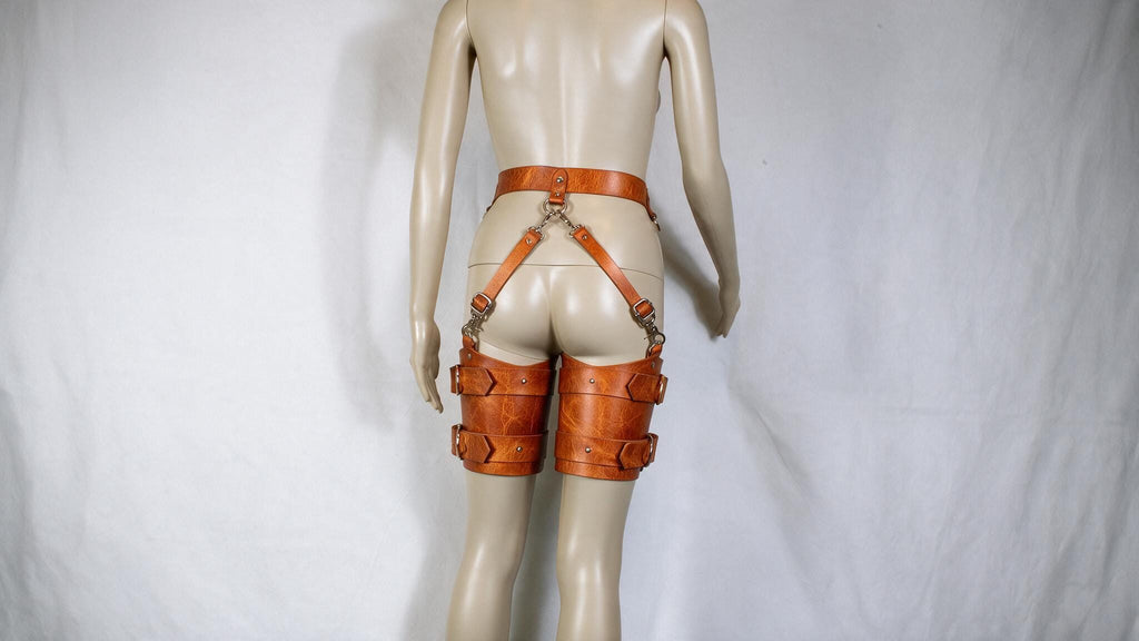 A mannequin wearing a pair of leather garter belts and garter cuffs.
