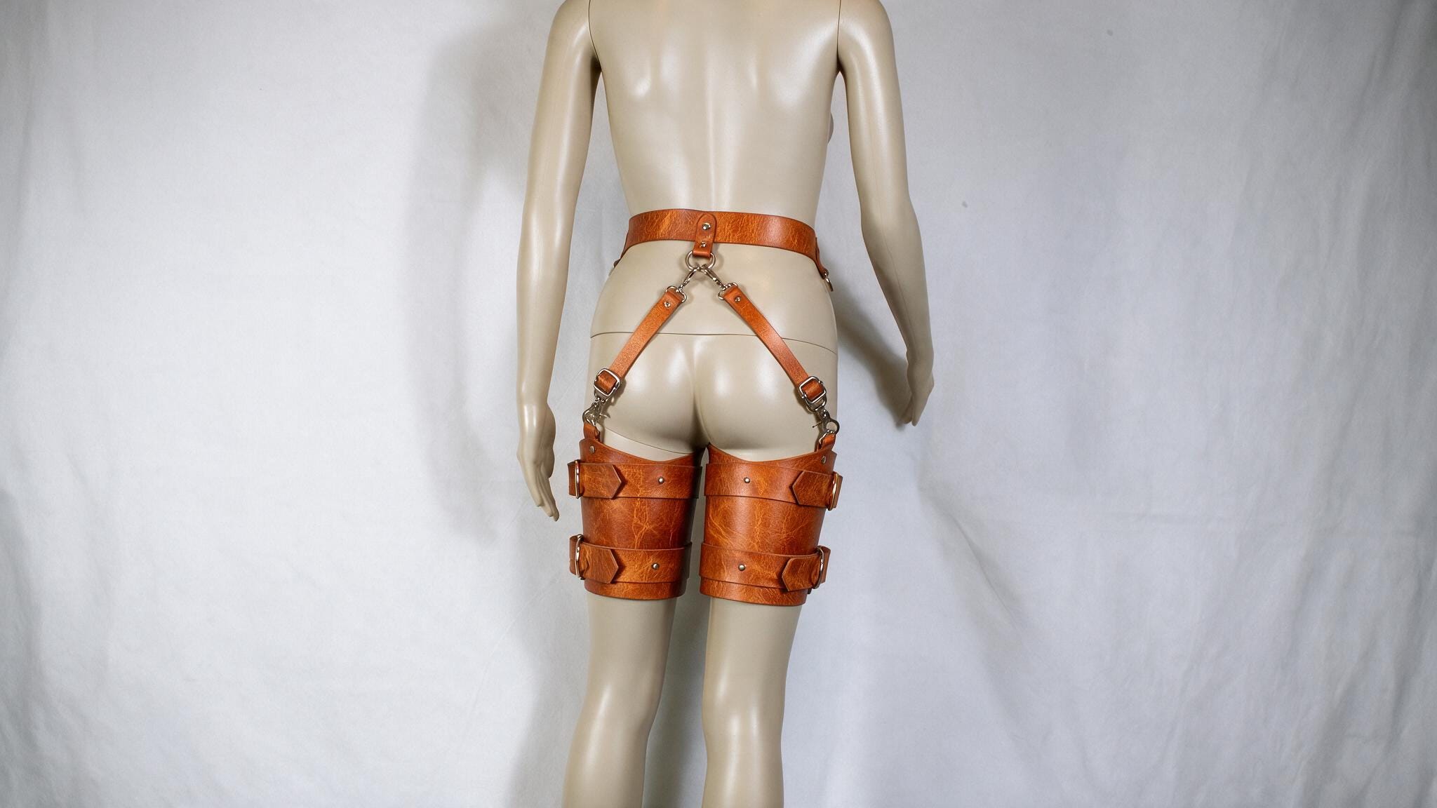 A mannequin wearing a pair of leather garter belts and garter cuffs.