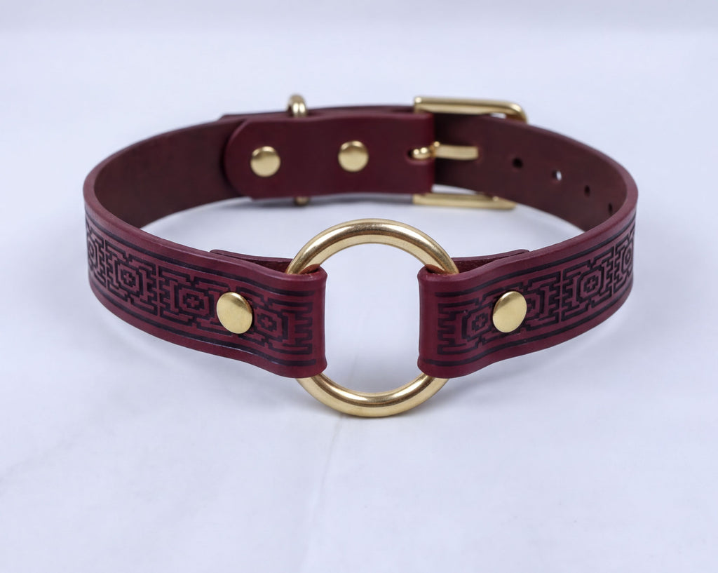 A burgundy leather choker collar with a gold-colored metal ring and buckle.
