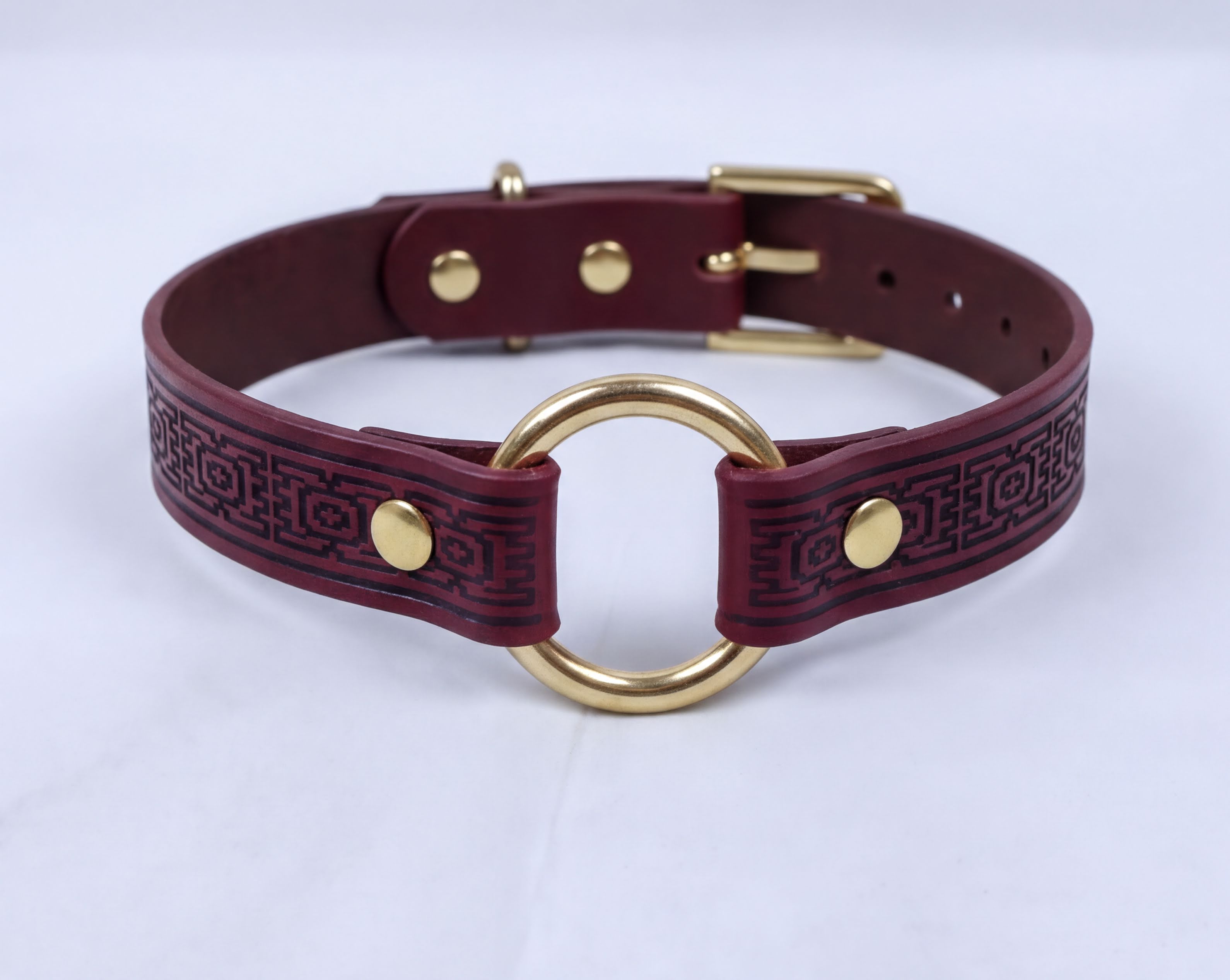A burgundy leather choker collar with a gold-colored metal ring and buckle.