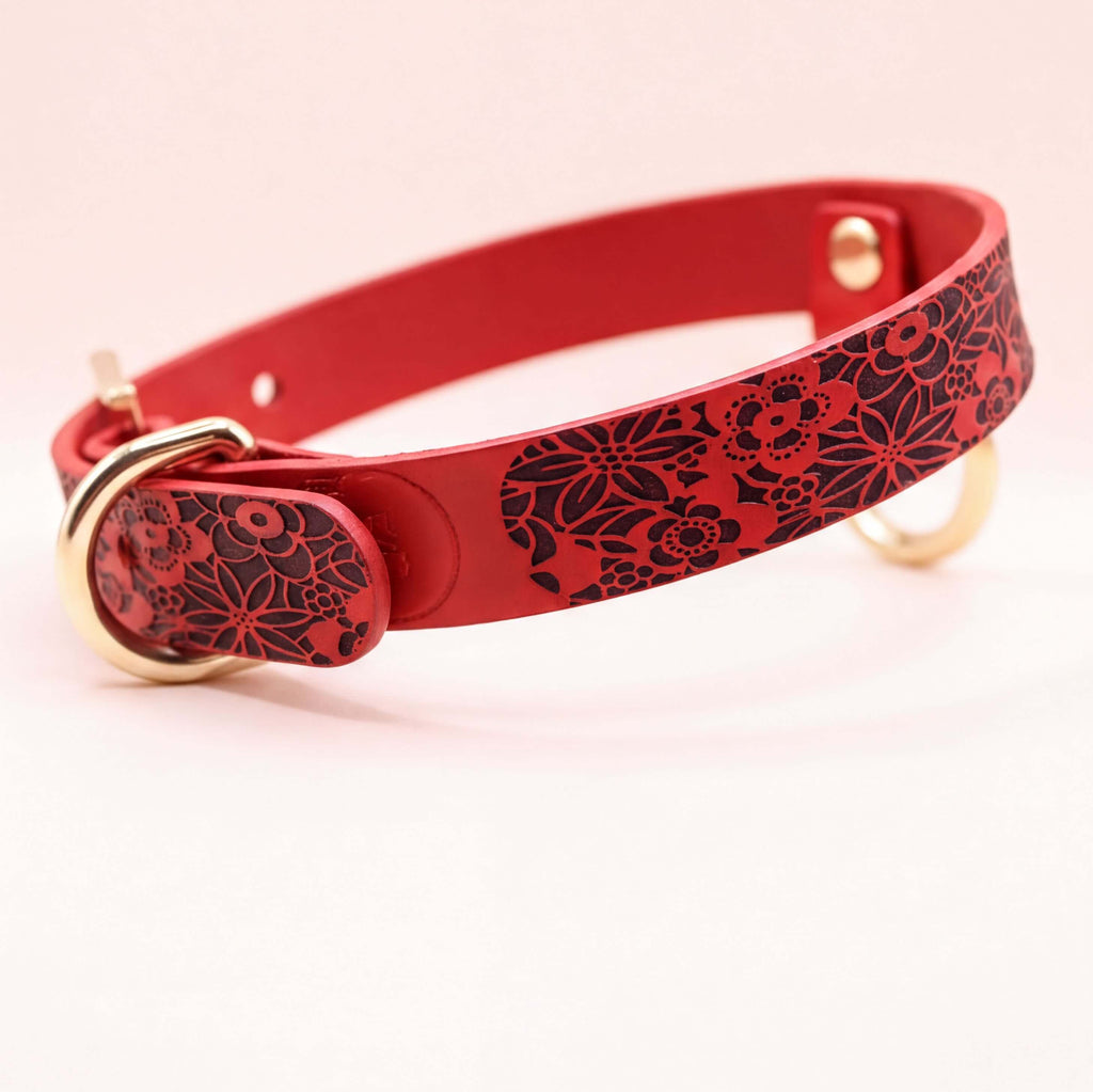 A red leather collar with a floral pattern on it.