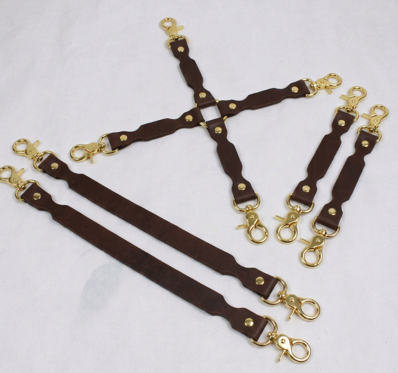 a collection of brown leather straps with gold-colored metal clasps, arranged in various orientations.