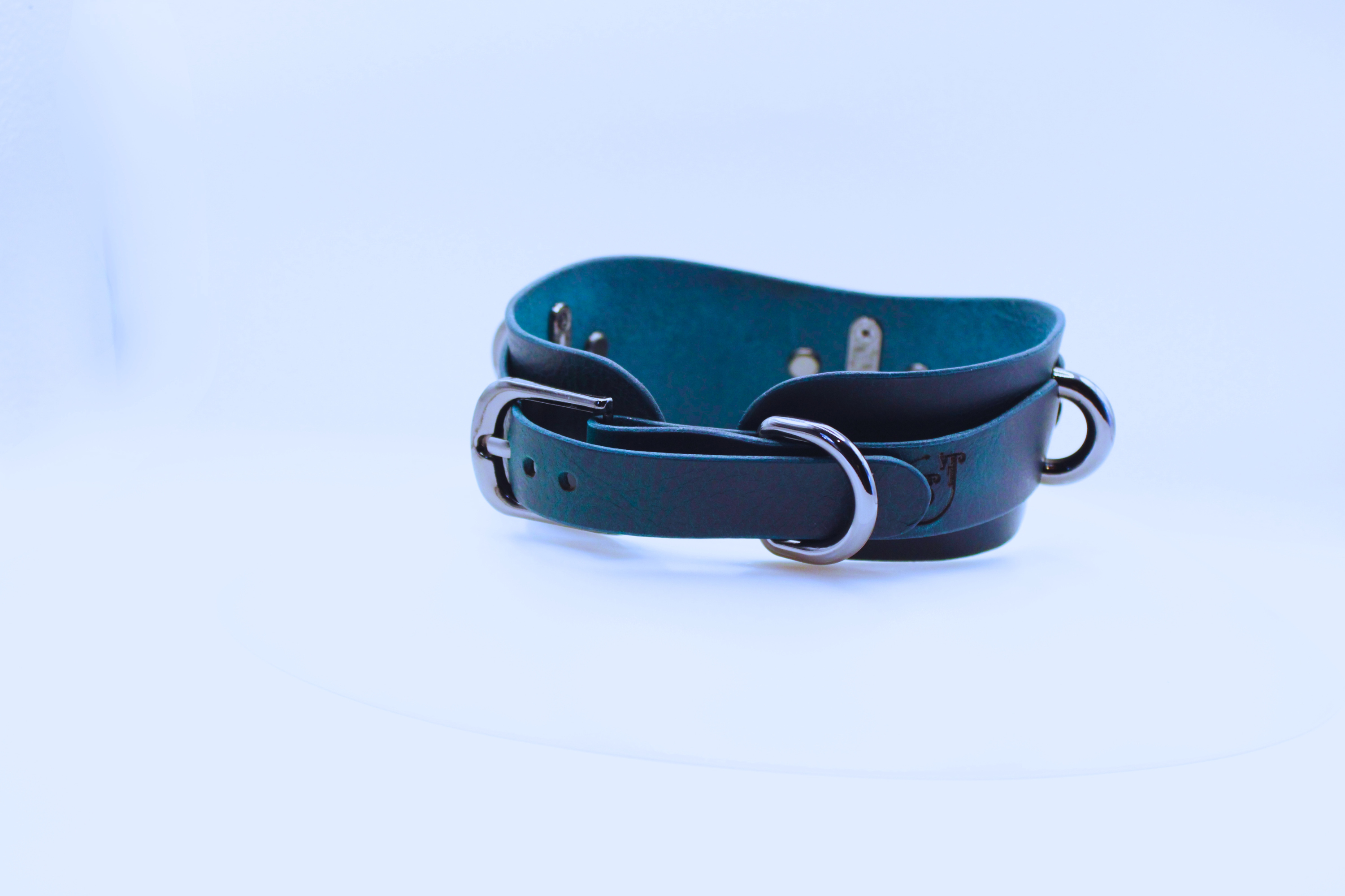 A dark blue leather belt with metal buckles and a metal clasp is shown against a white background.