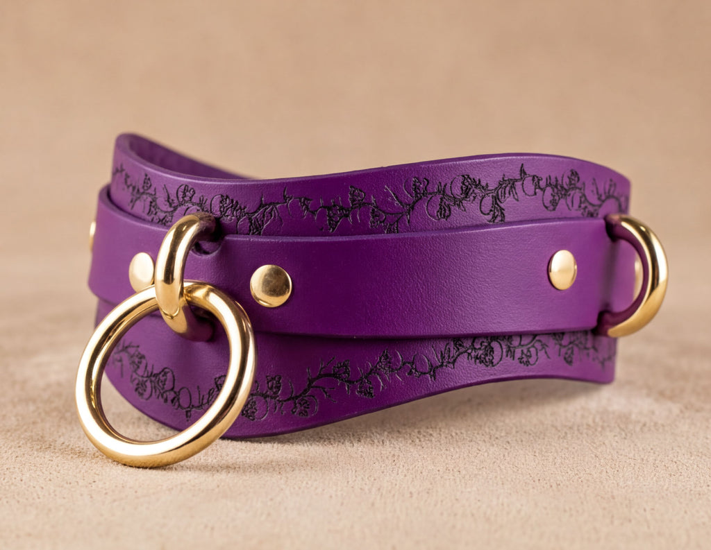 A purple leather choker necklace with gold-colored metal rings and a decorative pattern on the front.
