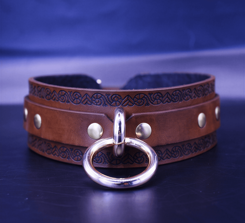 A brown leather choker necklace with a metal ring and decorative elements on the band.