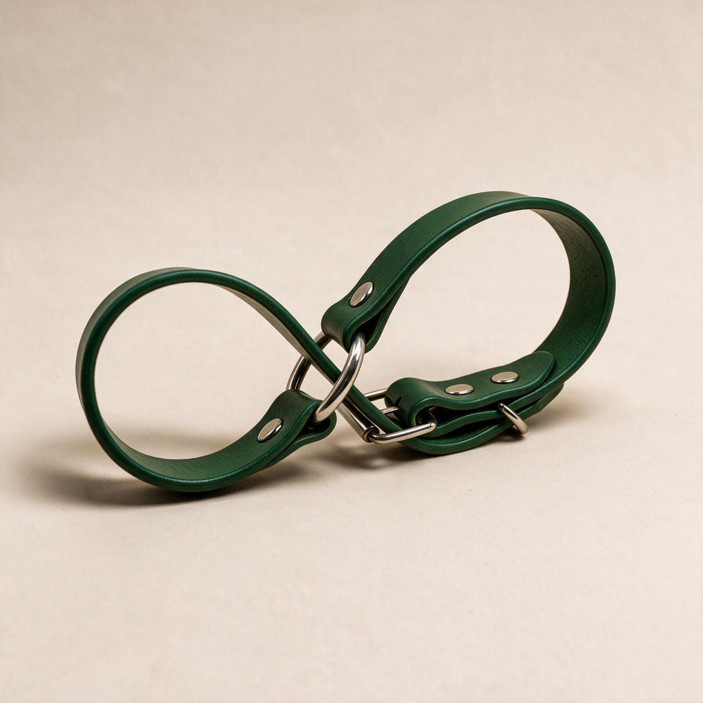 A green leather strap with metal buckles and clips is shown against a light background.