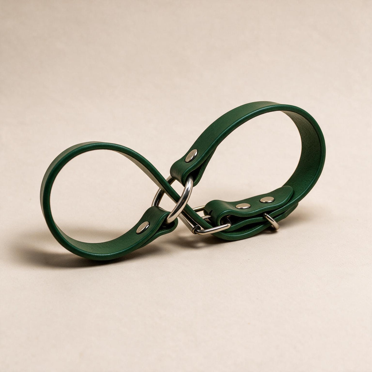 A green leather strap with metal buckles and clips is shown against a light background.