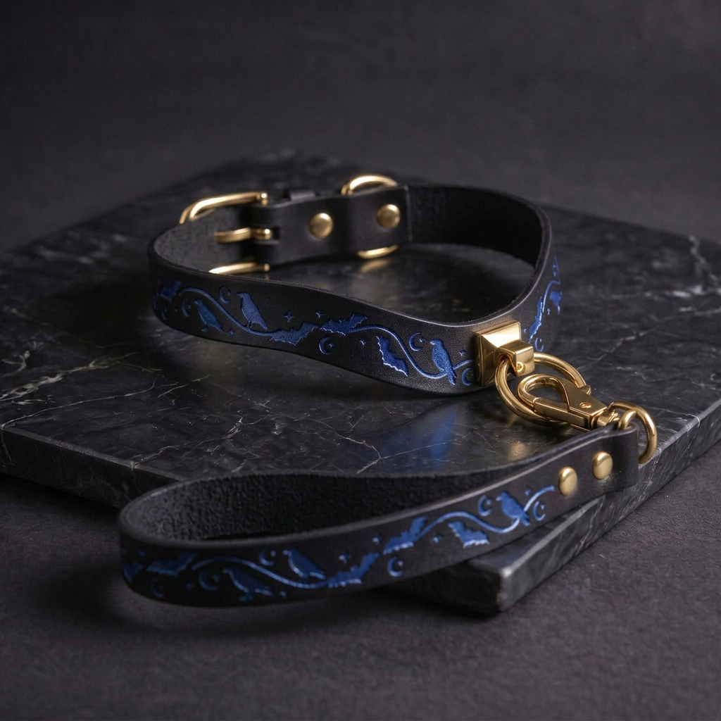 A black leather dog collar with a gold-colored buckle and a matching leash is displayed on a black marble surface.