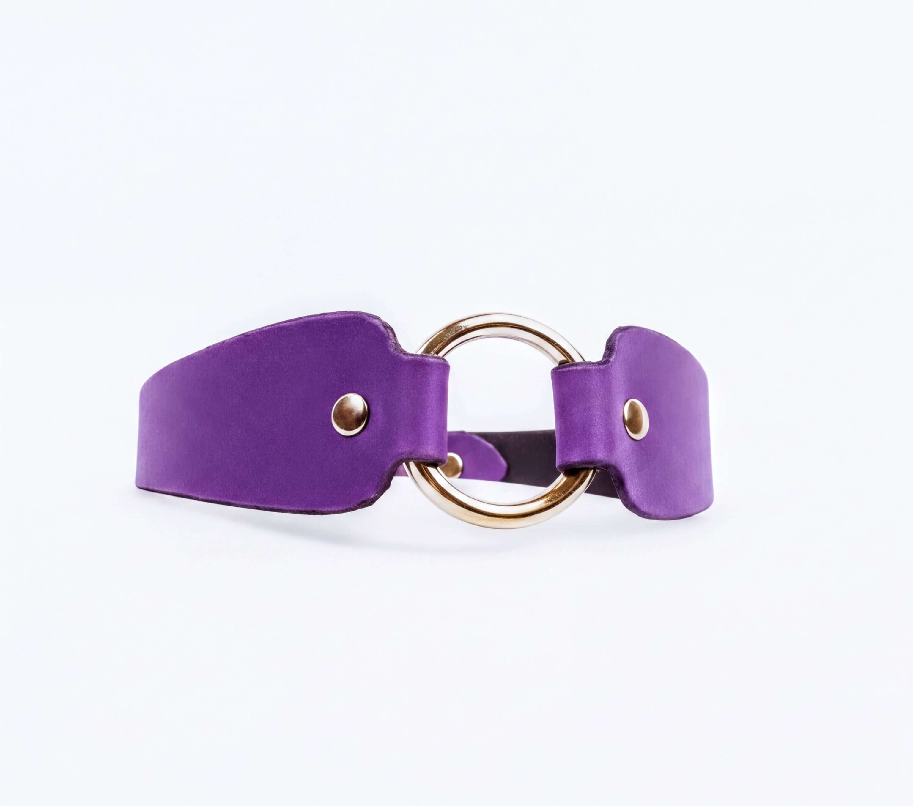 A purple leather choker necklace with a gold-colored circular buckle.