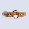 A tan leather collar with a floral design and metal ring, featuring two silver buttons.