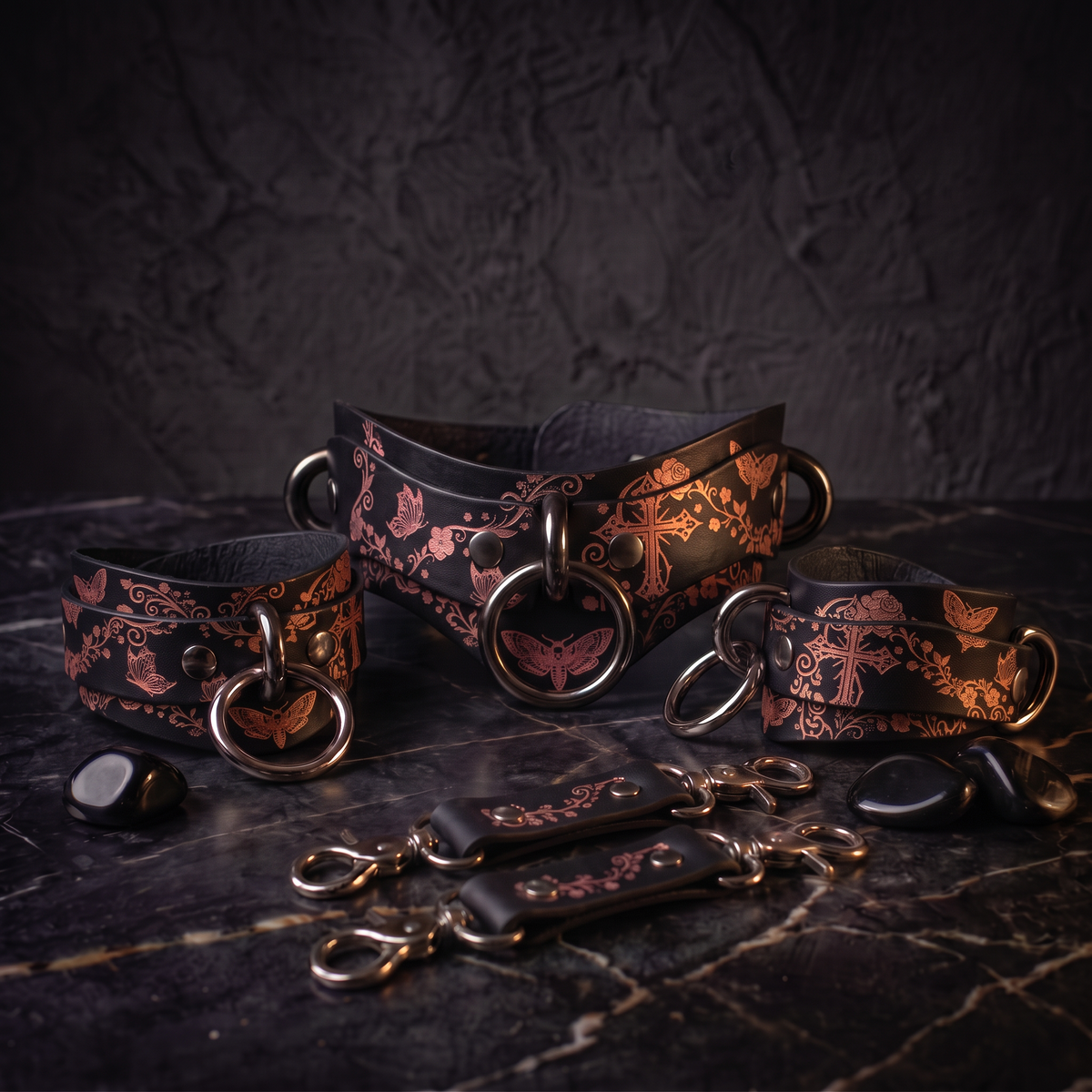 a collection of leather accessories, including a corset, leather straps, and a corset ring, arranged on a dark surface.