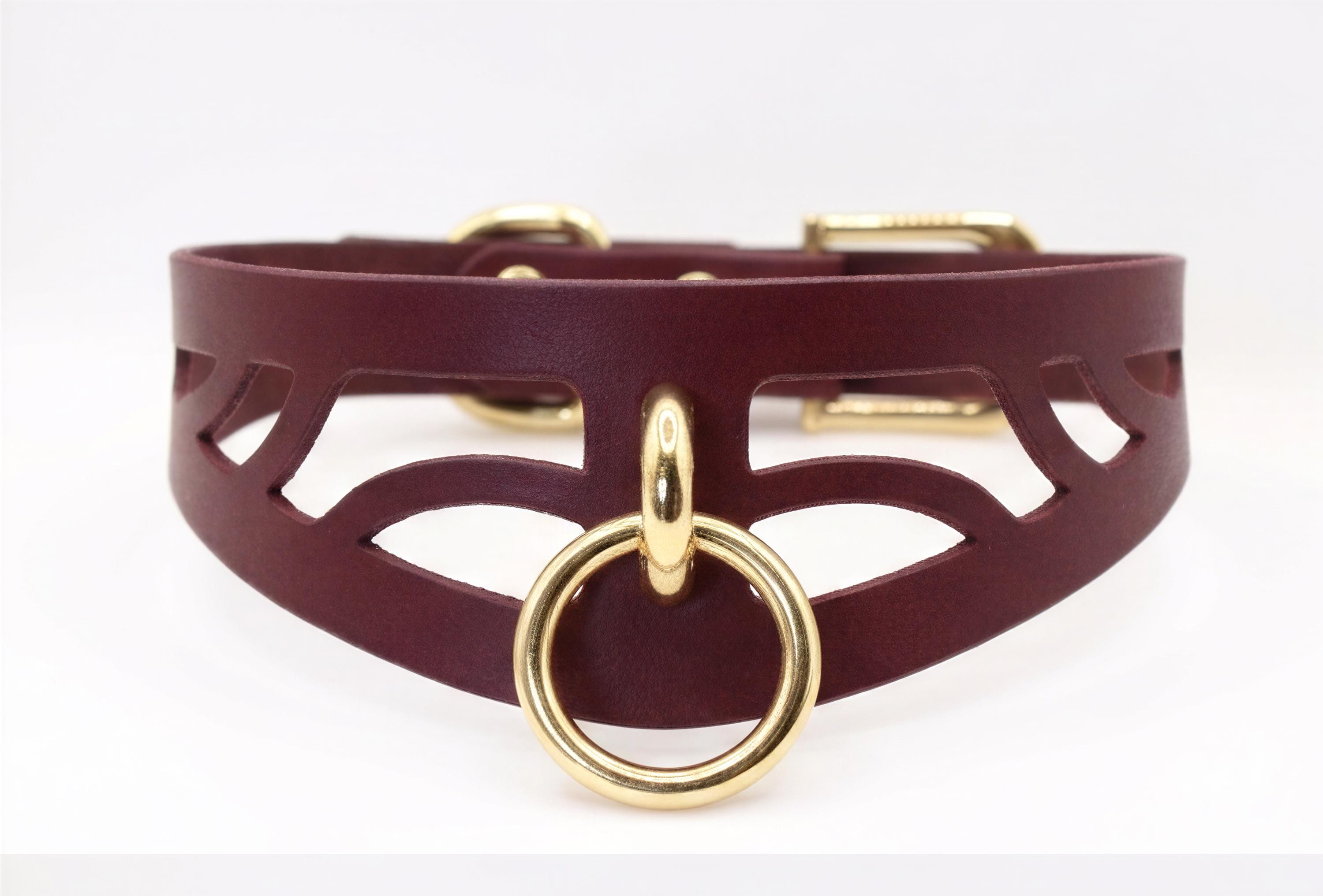 A burgundy leather choker necklace with a gold-colored metal ring and buckle.