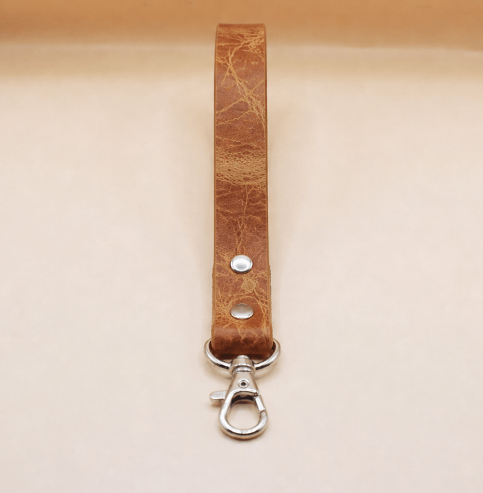 A brown leather strap with a metal clasp and hook attached to it.