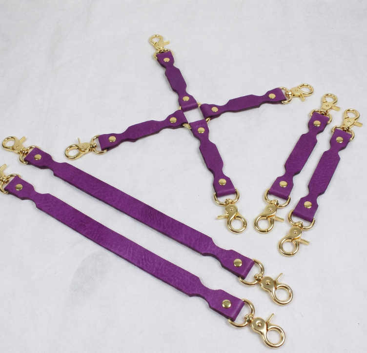 a collection of purple leather straps with gold-colored metal clasps, arranged in a way that they appear to be connected or interlocked.