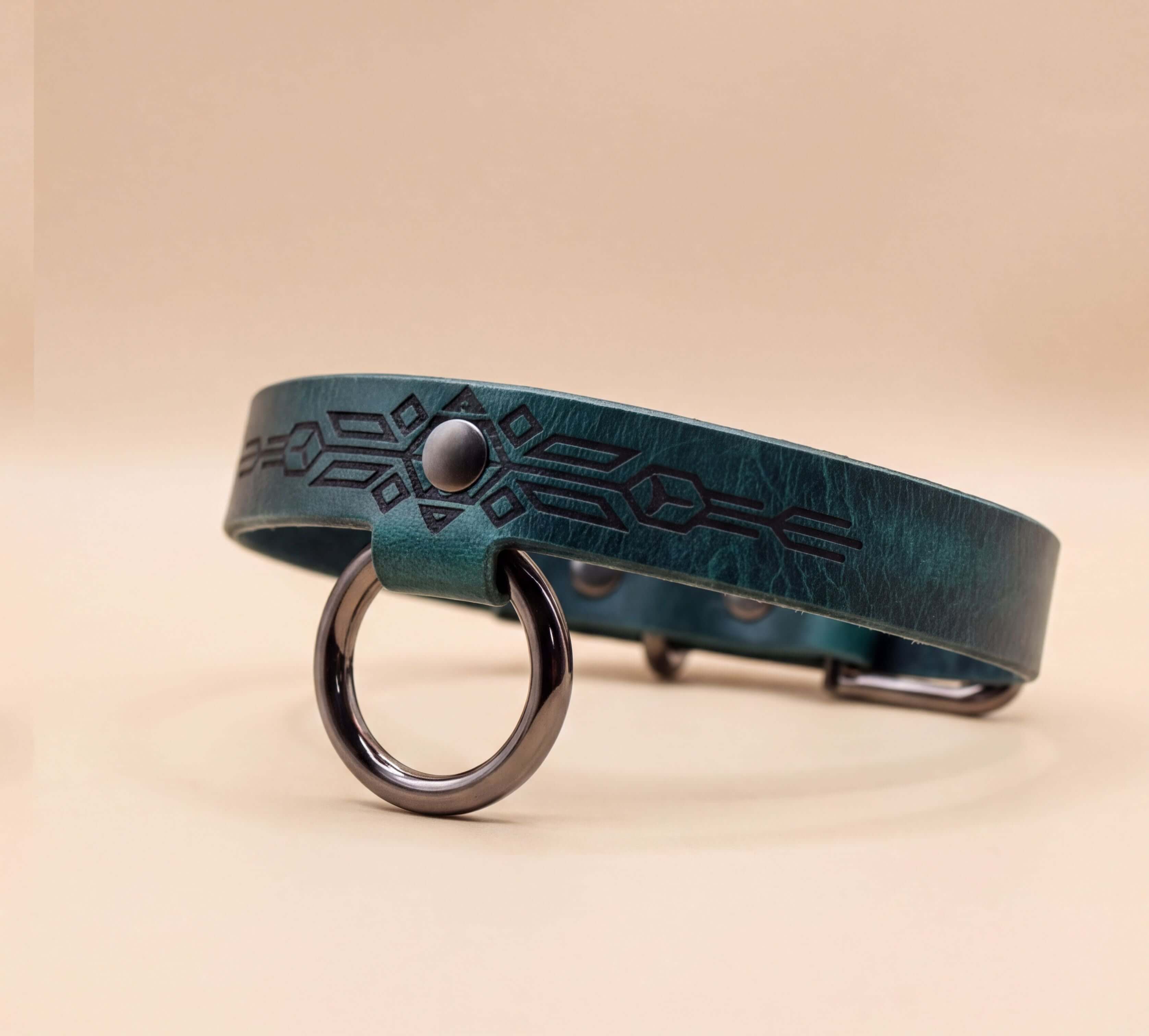 A green leather collar with a metal ring and a geometric pattern design.