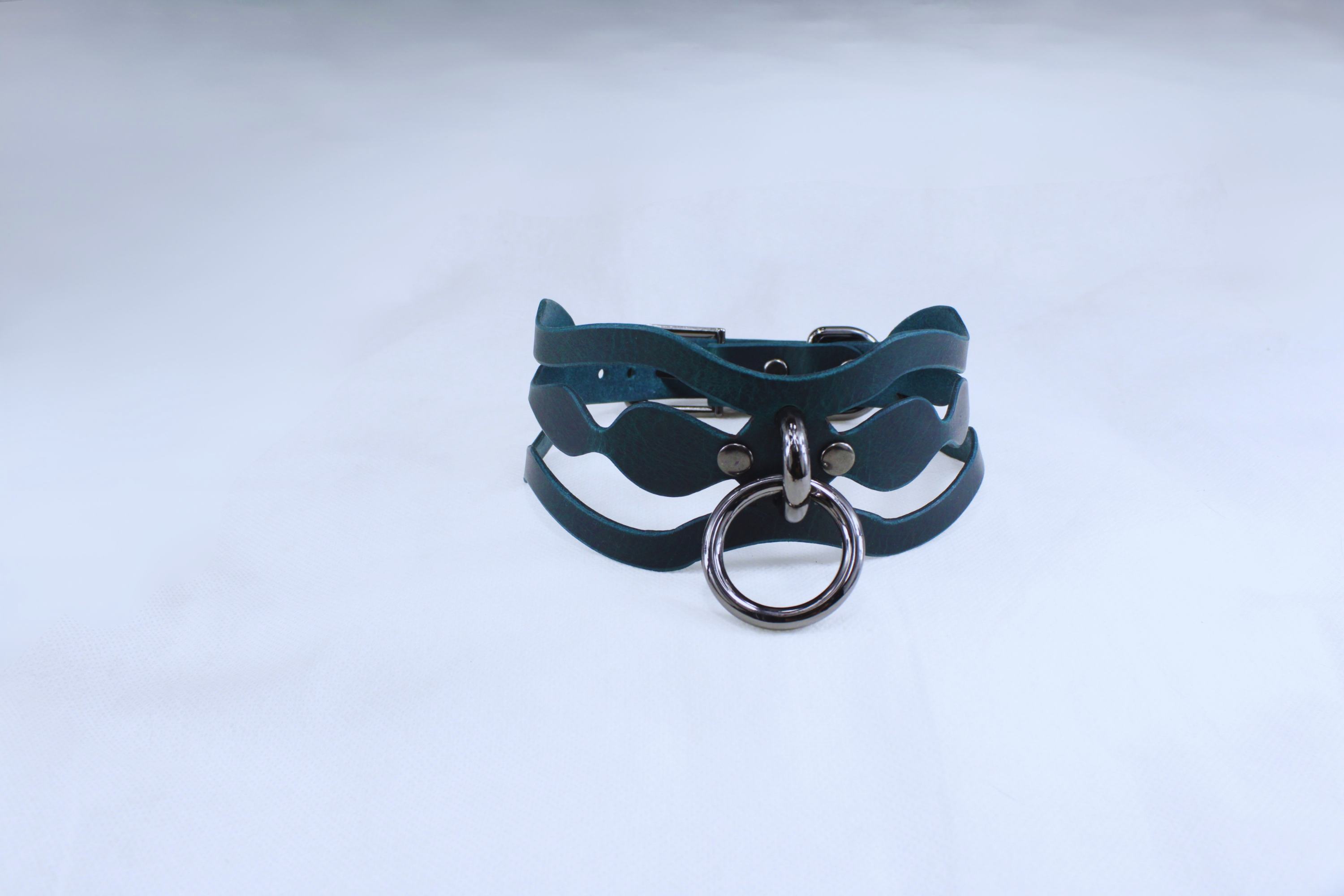 A dark green leather choker necklace with a metal ring and buckle.