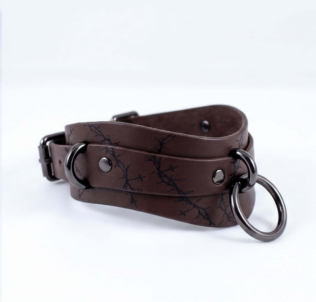 A brown leather choker necklace with metal rings and a metal clasp.