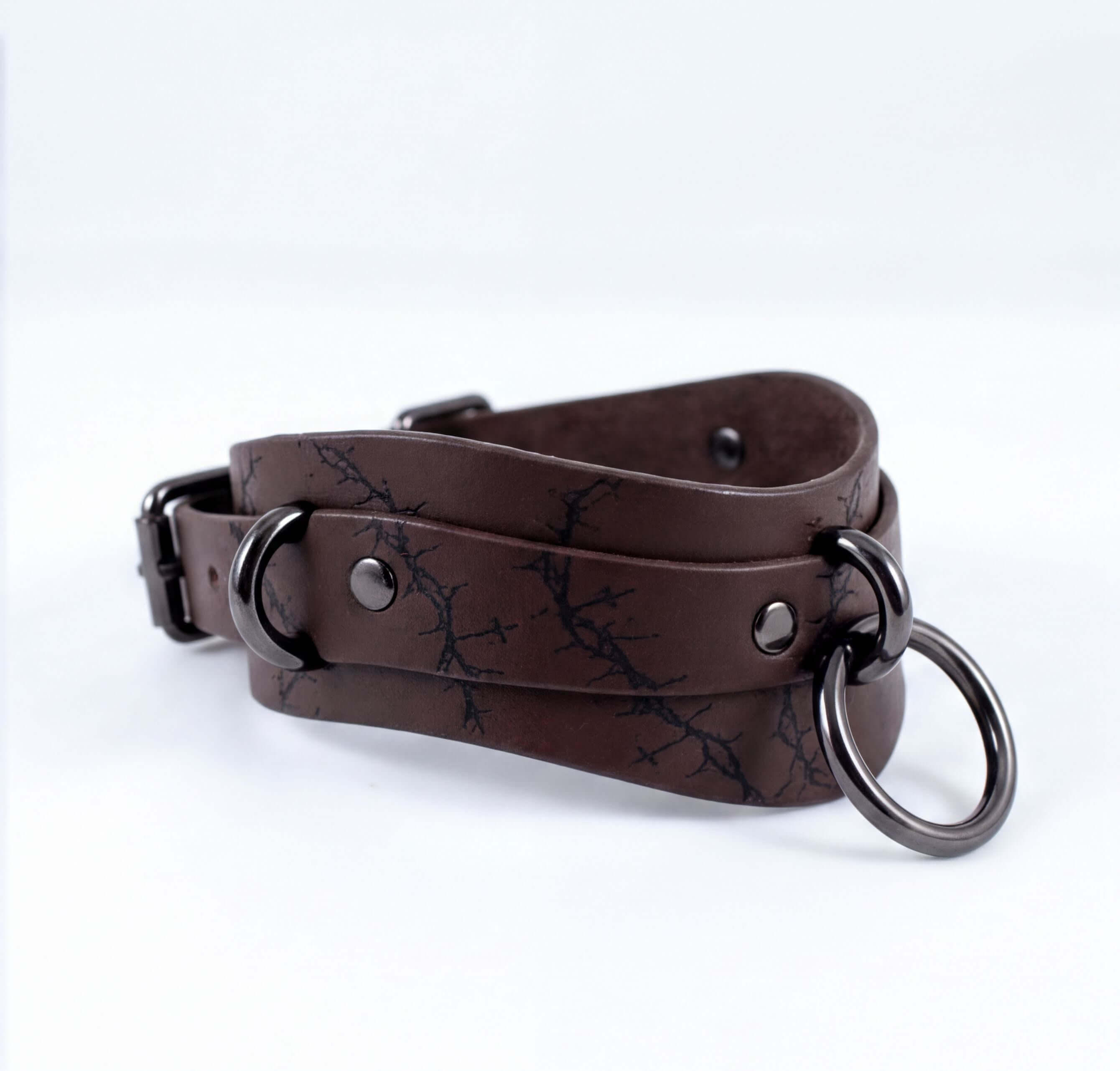 A brown leather choker necklace with metal rings and a metal clasp.