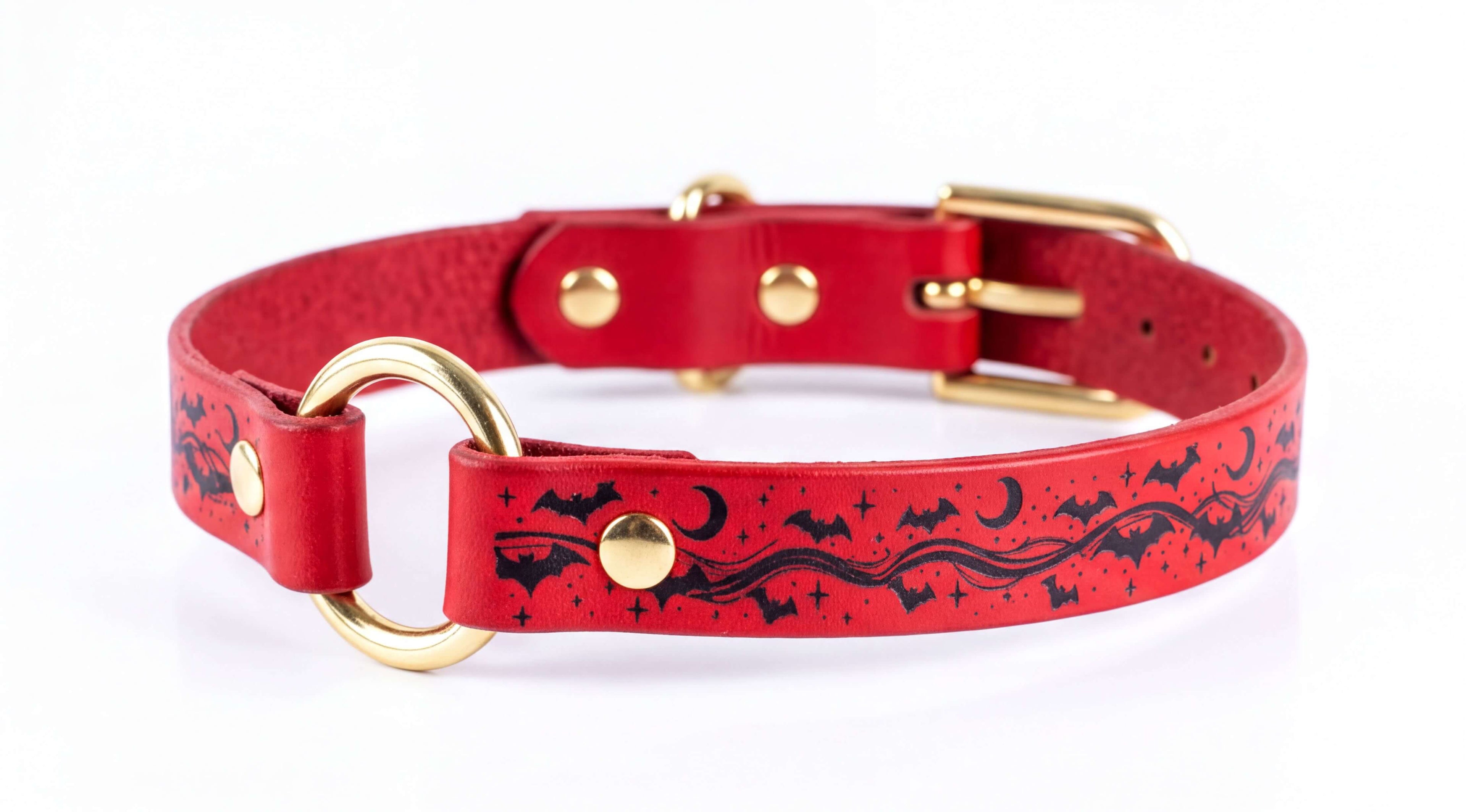 A red leather dog collar with a gold buckle and a bat-themed design.