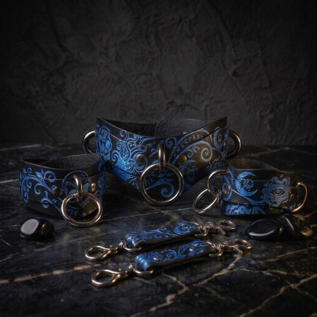 A collection of ornate leather straps with intricate blue floral designs, arranged on a dark surface.
