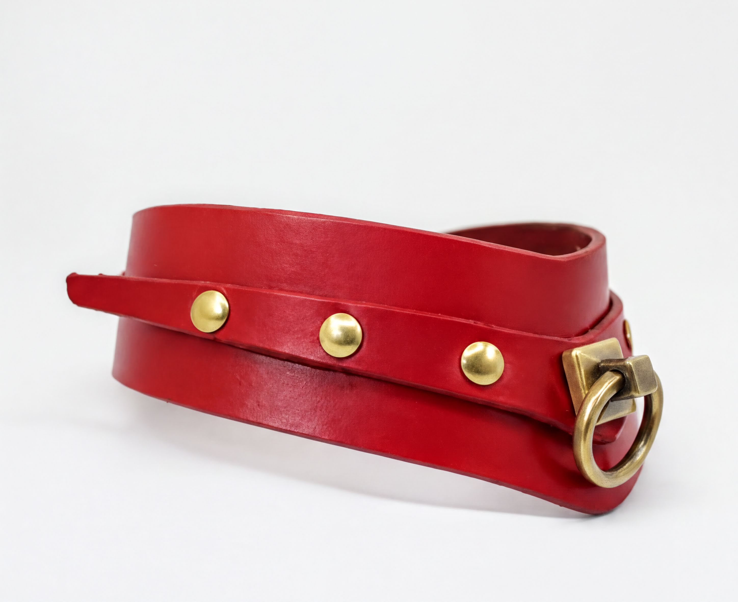 A red leather choker with gold hardware, including a buckle and three metal studs, is shown against a white background.