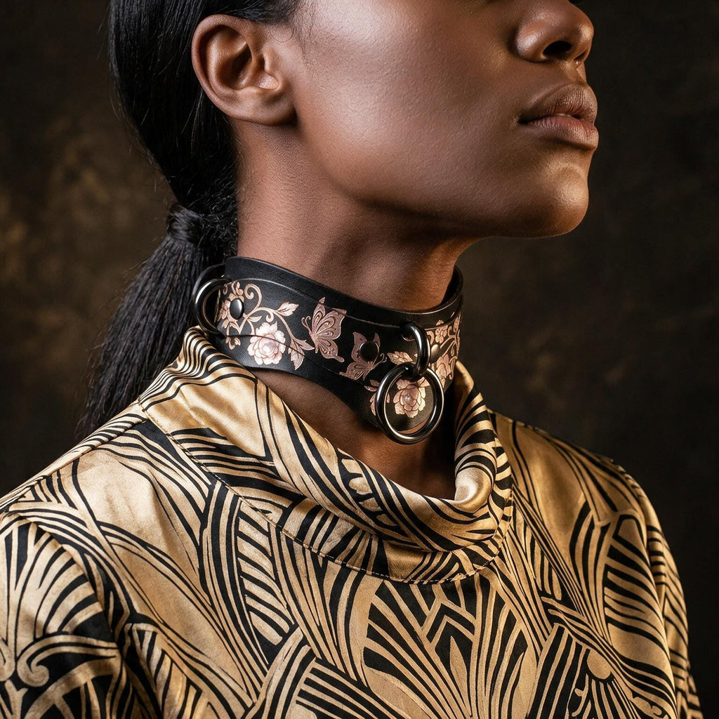 A close-up of a woman's neck and chest area, featuring a decorative choker necklace with floral patterns and a metallic ring.
