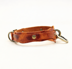 A brown leather collar with metal rings and a buckle, displayed against a white background.