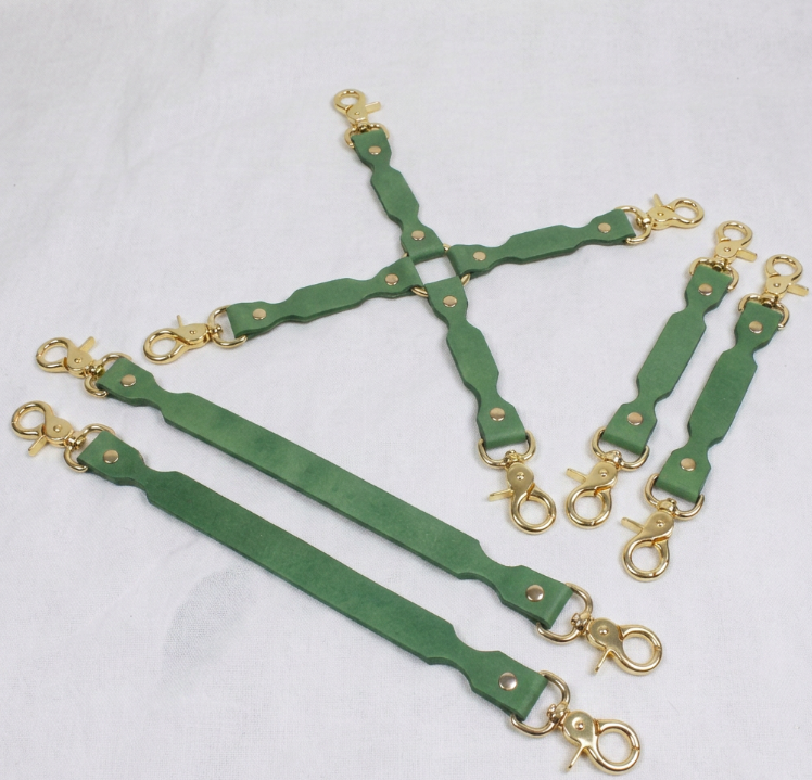 a collection of green leather straps with gold-colored metal clasps, arranged in various orientations.