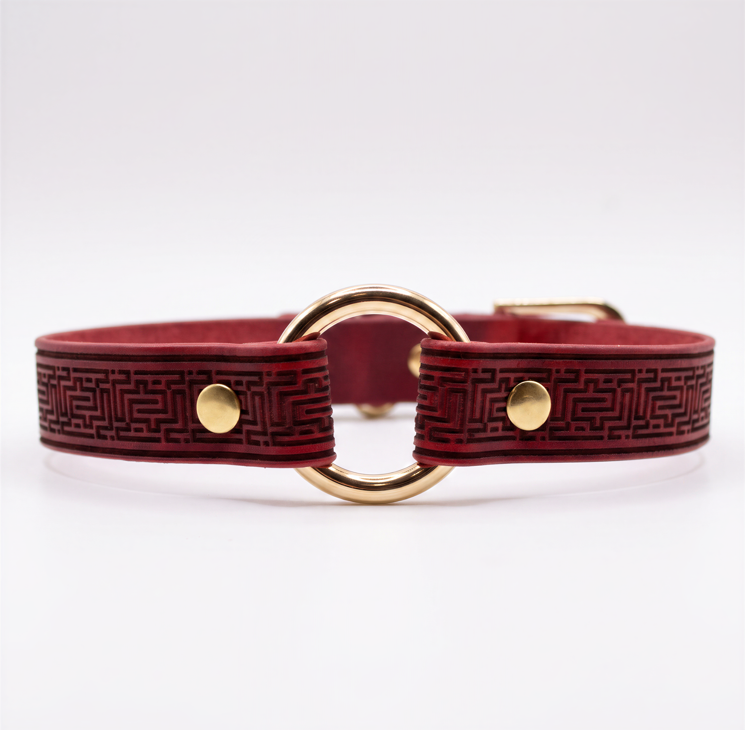 A burgundy leather collar with a gold-colored metal ring and two gold-colored metal fasteners.
