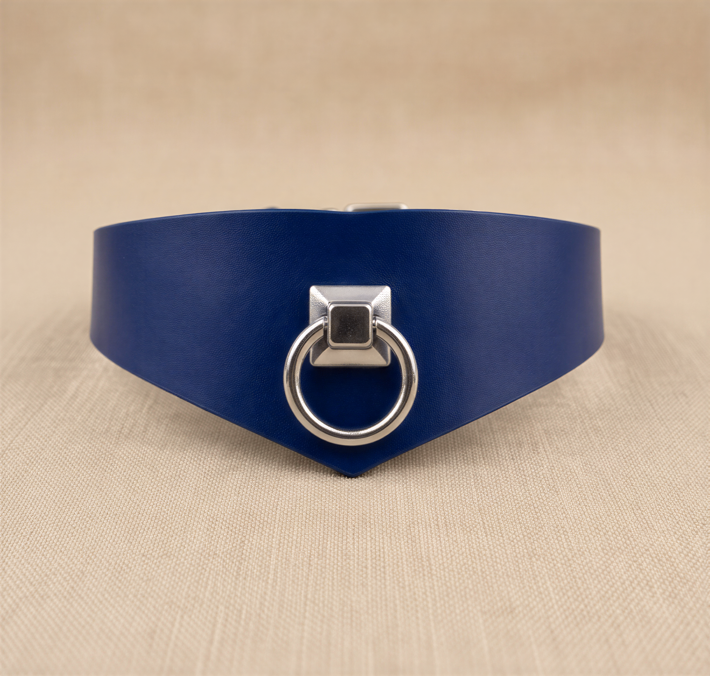 A blue leather choker necklace with a silver metal ring and a square metal piece on the front.