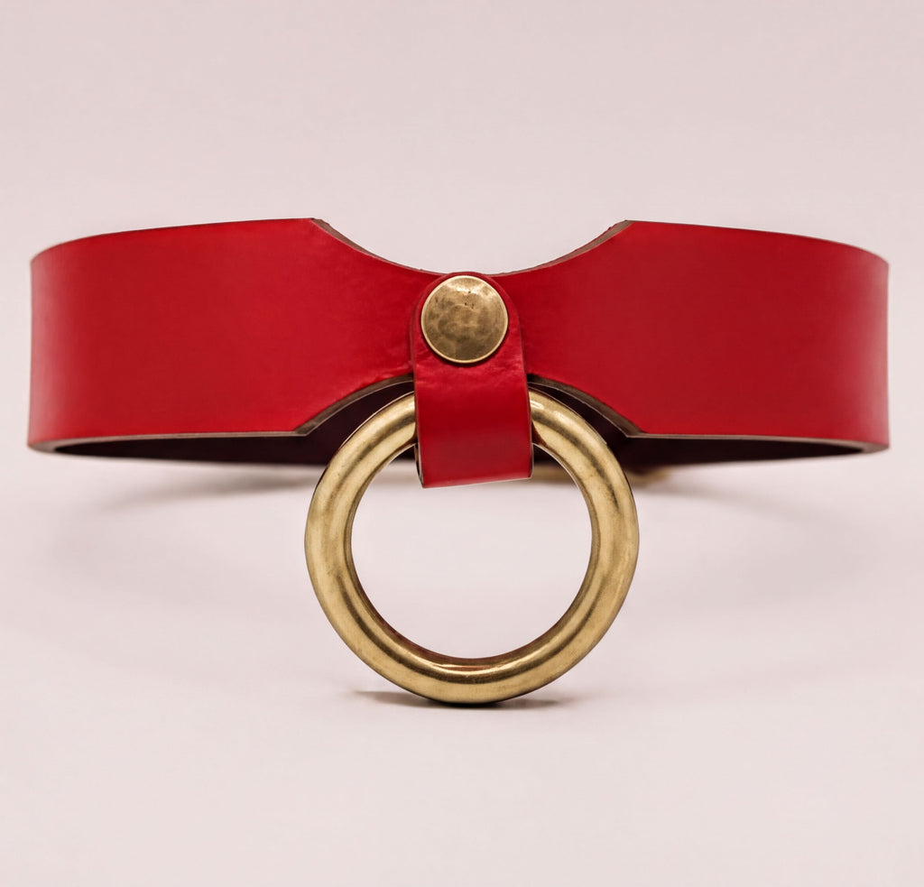 A red leather choker necklace with a brass ring and a gold-colored buckle.