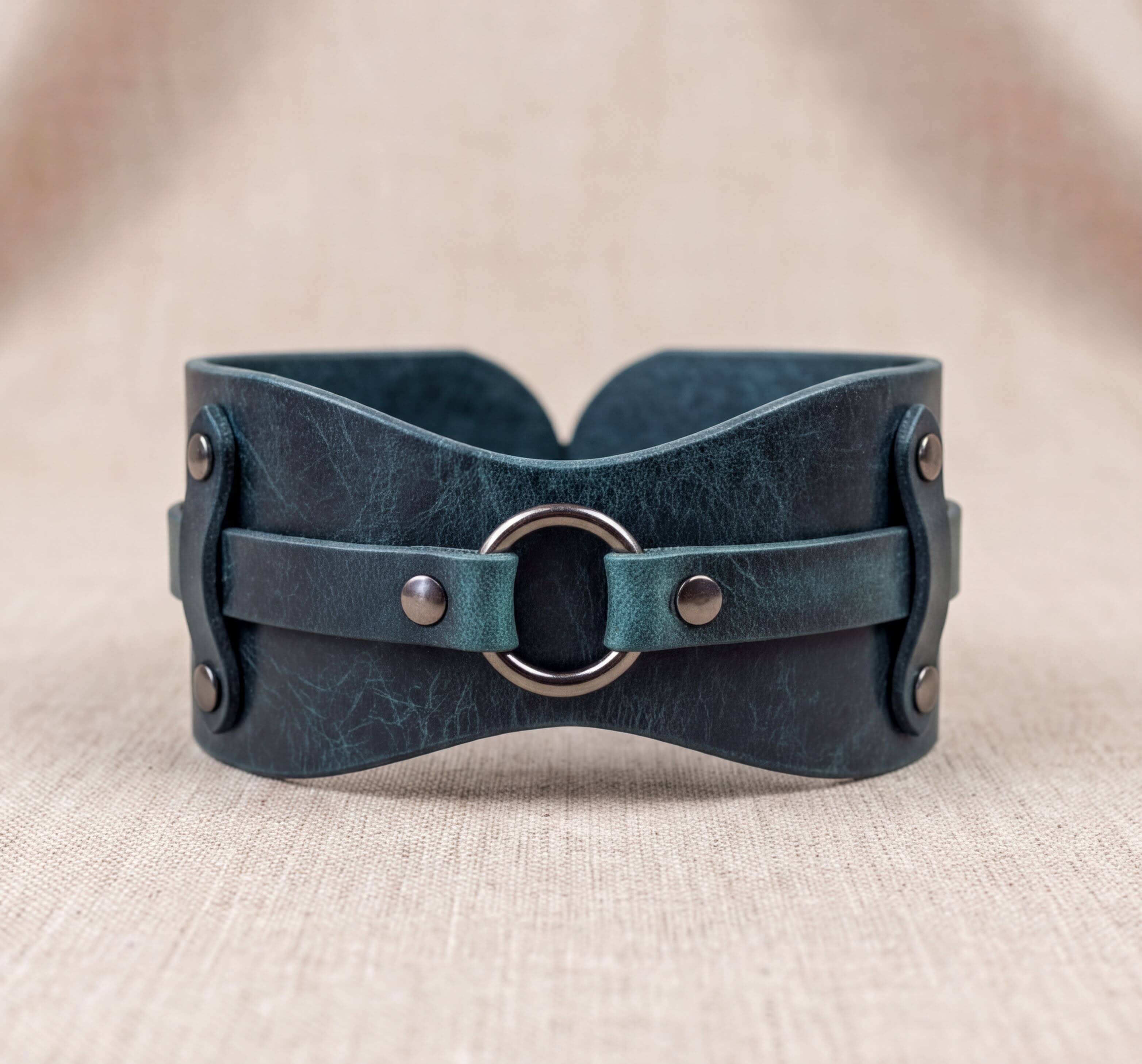A dark green leather corset with metal fasteners and a circular metal buckle.