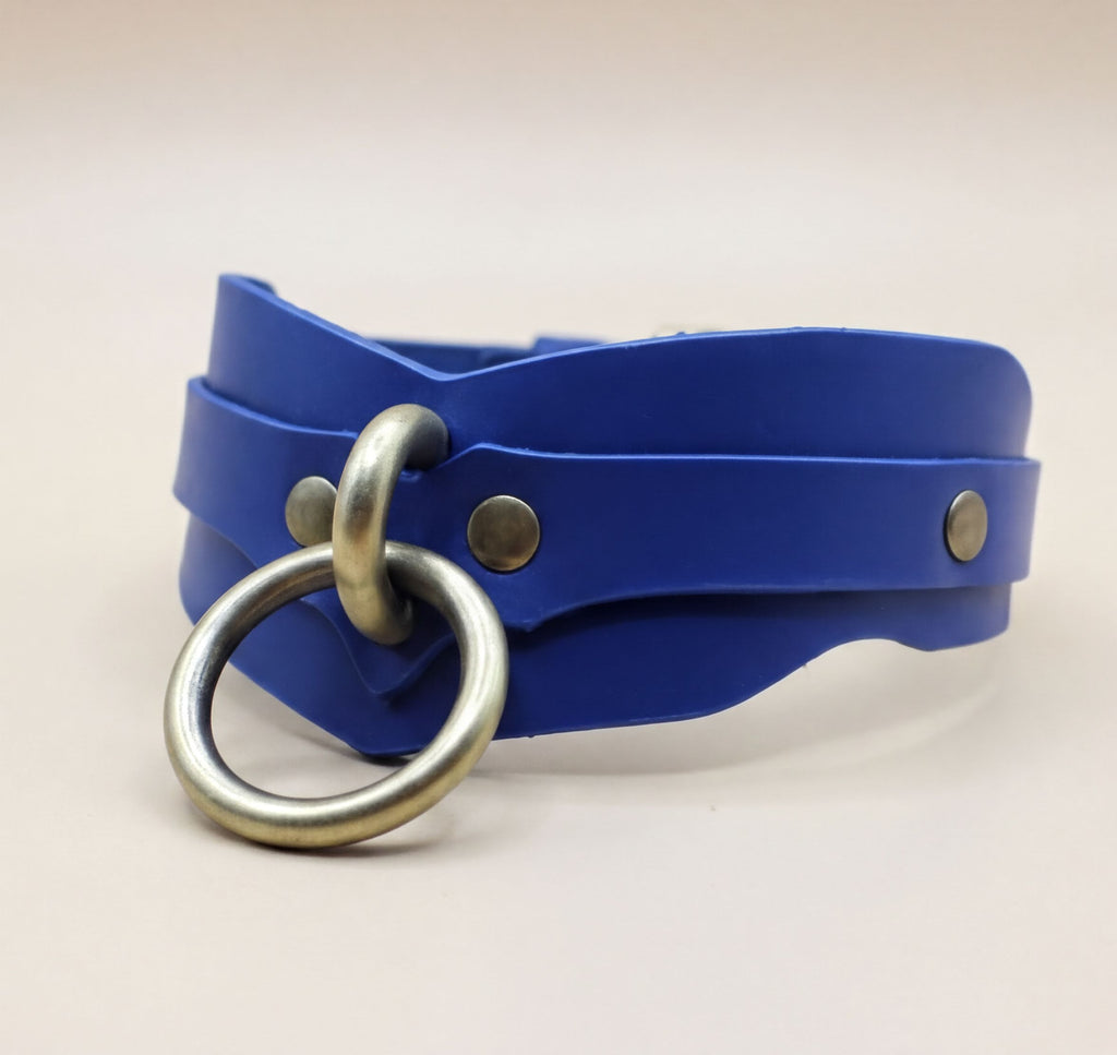 A blue leather choker necklace with a metal ring and two metal studs on the front.
