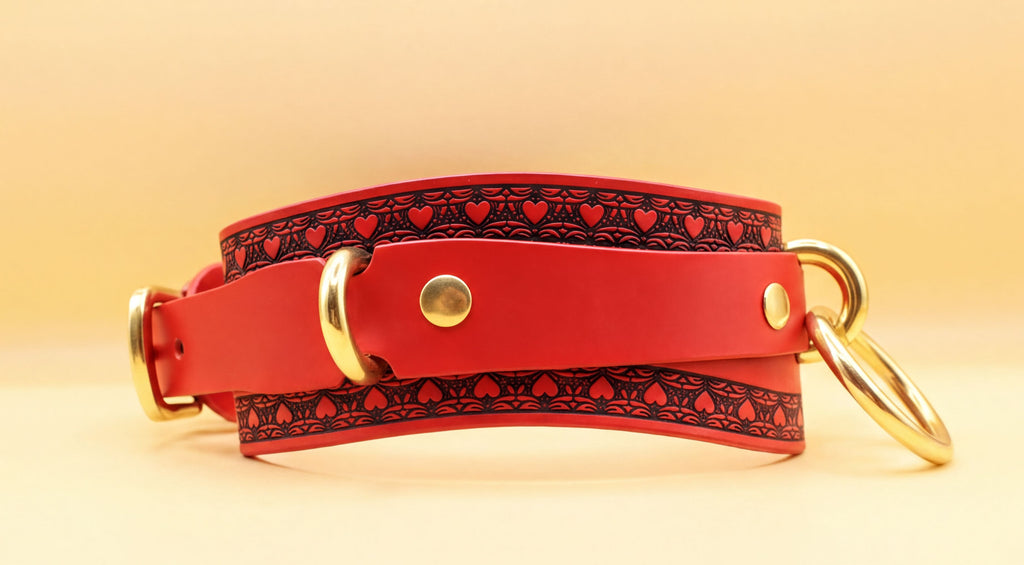 A red leather choker with a black heart pattern and gold-colored metal rings is shown against a yellow background.