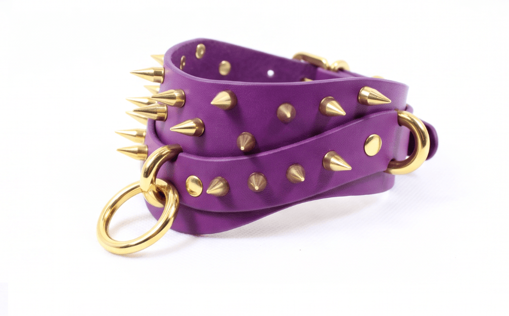 A purple leather strap with gold spikes and rings, creating a bold and edgy accessory.