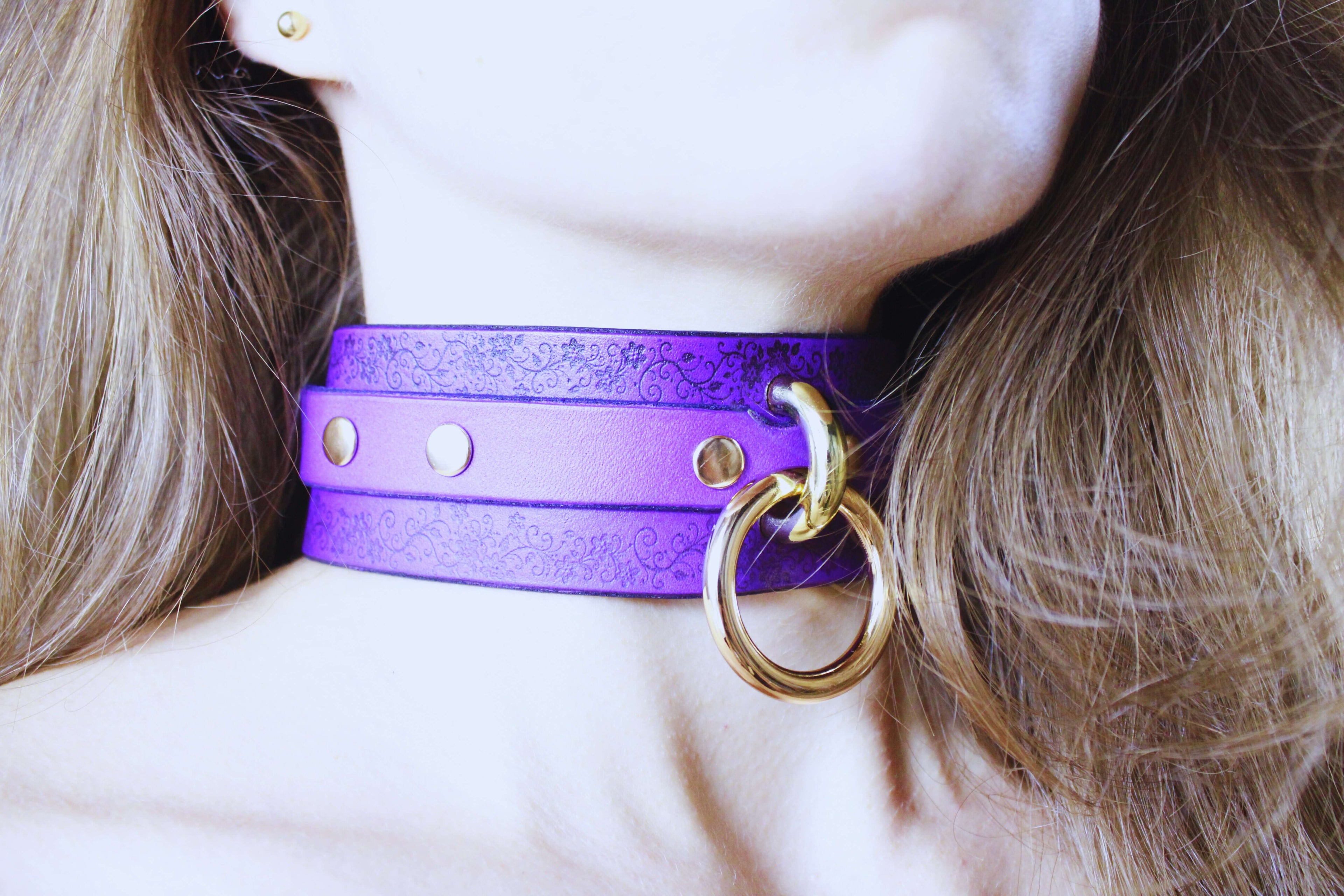 Floral Pattern Submissive Collar in purple leather worn as a discreet day choker, featuring a golden ring and studs.
