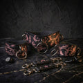 a collection of leather straps and charms with intricate designs, including floral patterns and celestial motifs, arranged on a dark surface.