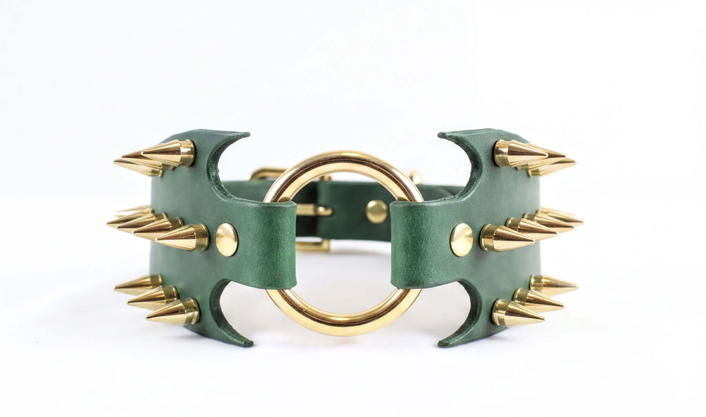 A green leather choker necklace with gold spikes protruding from it.