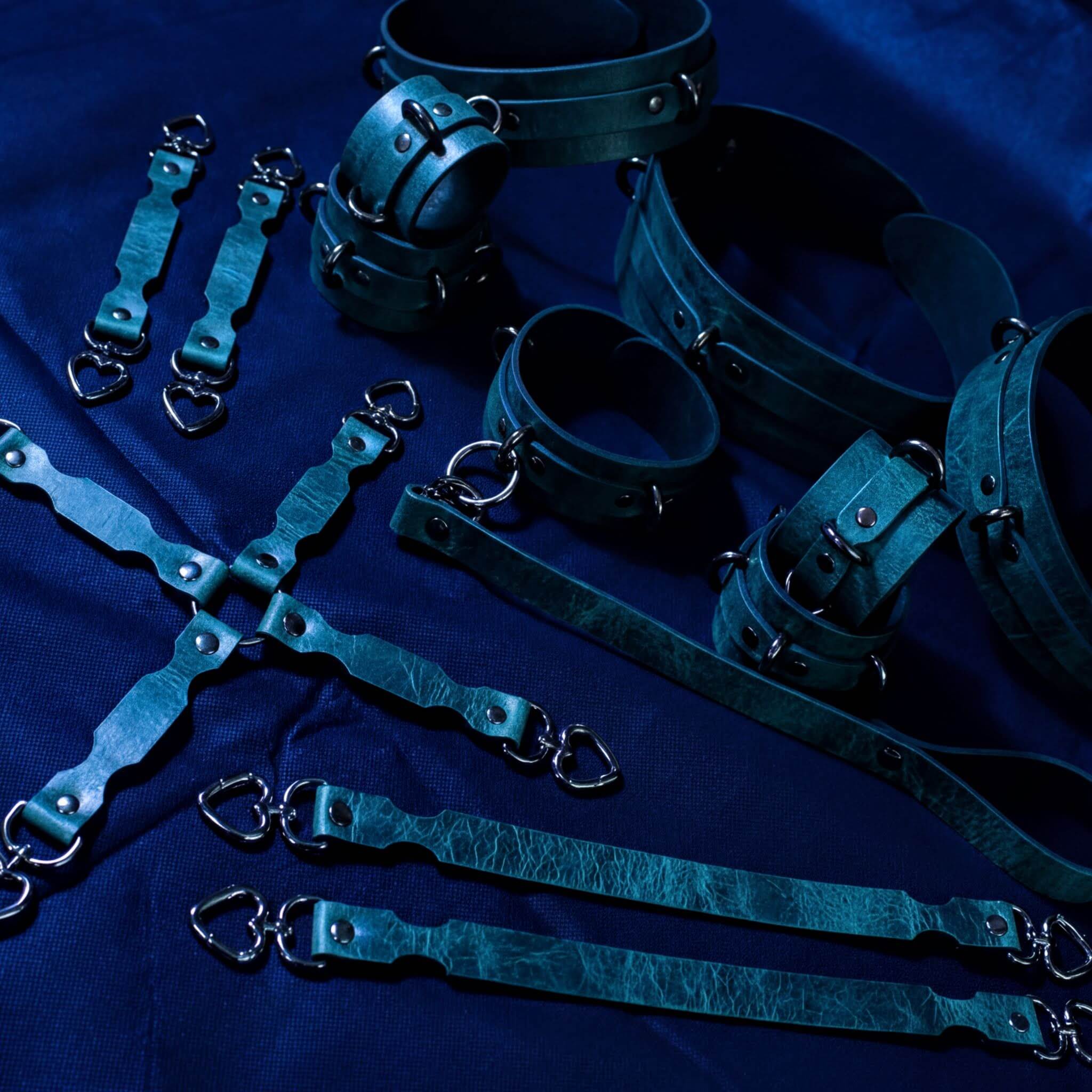 a collection of leather straps and restraints arranged on a dark blue background.