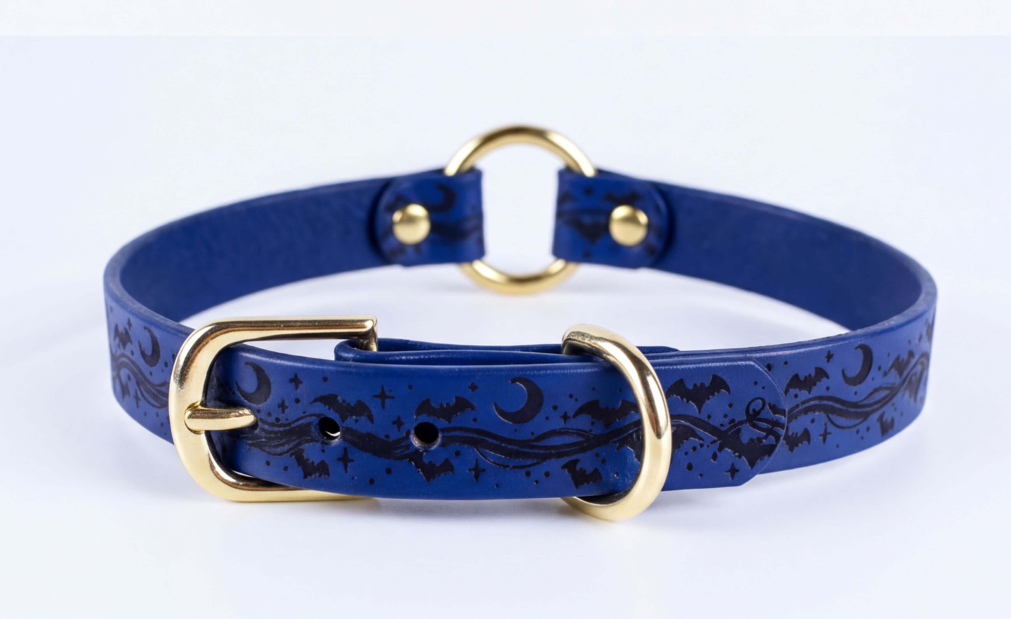 A blue leather collar with a gold buckle and a bat and moon design.