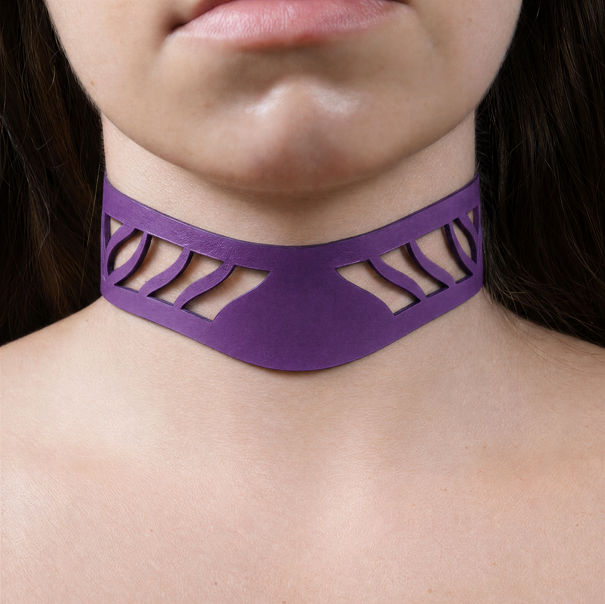 A close-up of a person's neck and chest area wearing a purple choker necklace with a unique cutout design.