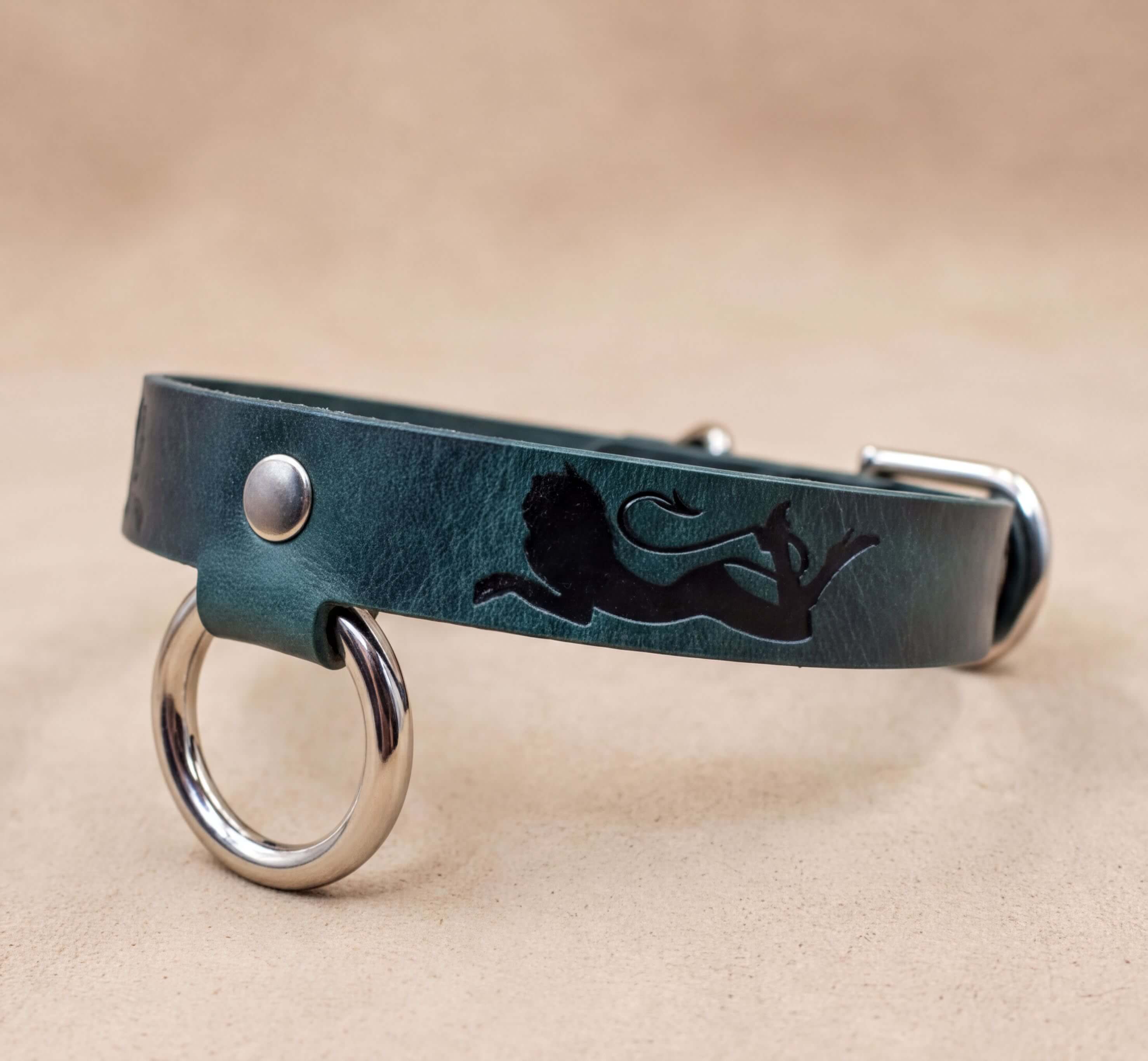 A green leather dog collar with a lion silhouette and metal rings on the ends.