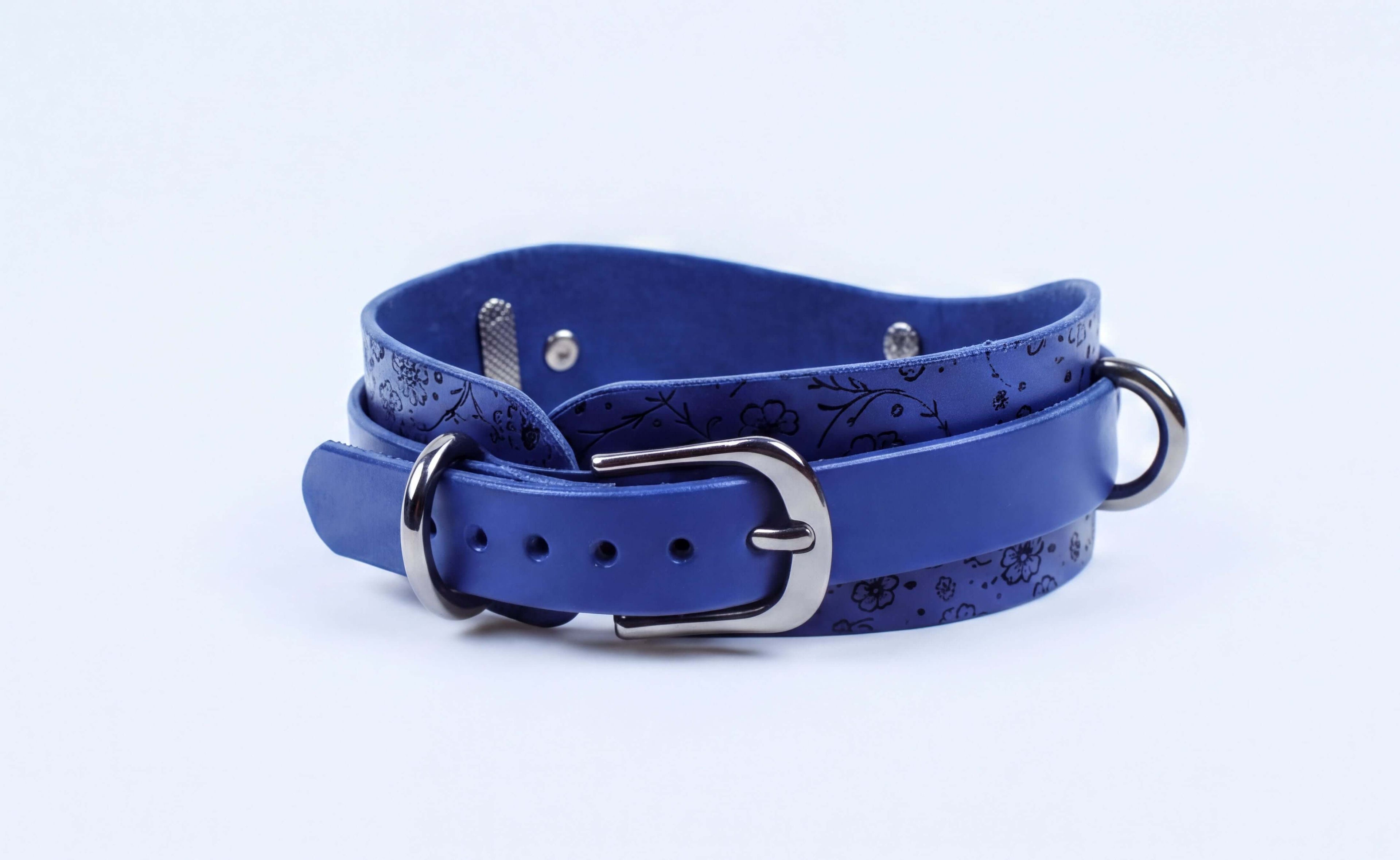 A blue leather choker collar with a metal buckle and a floral pattern on the strap.