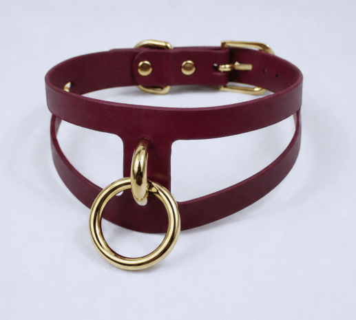 A burgundy leather choker necklace with a gold ring and buckle.